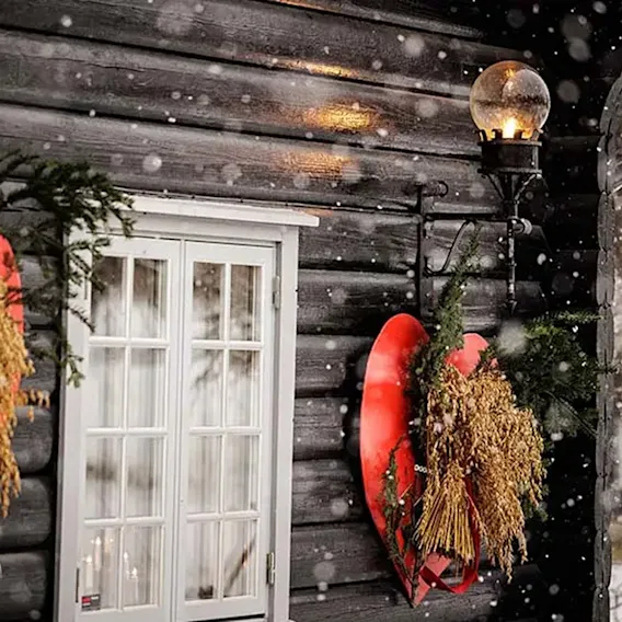 Tradisjonelt julenek festet på røde trehjerter på en mørk tømmervegg i dalende snø.