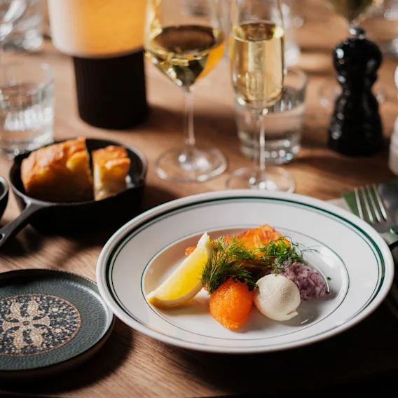 Et vakkert dekket spisebord med et deilig måltid, vin og brød, klart for en hyggelig matopplevelse.