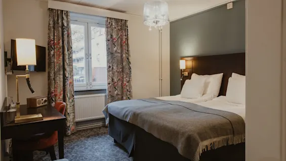 A cozy hotel room at Home Hotel Kung Oscar with a comfortable bed and a functional workspace.