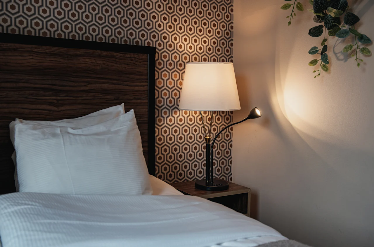 A warm and inviting bedroom with a bed, a patterned wall, and two lamps illuminating the space.