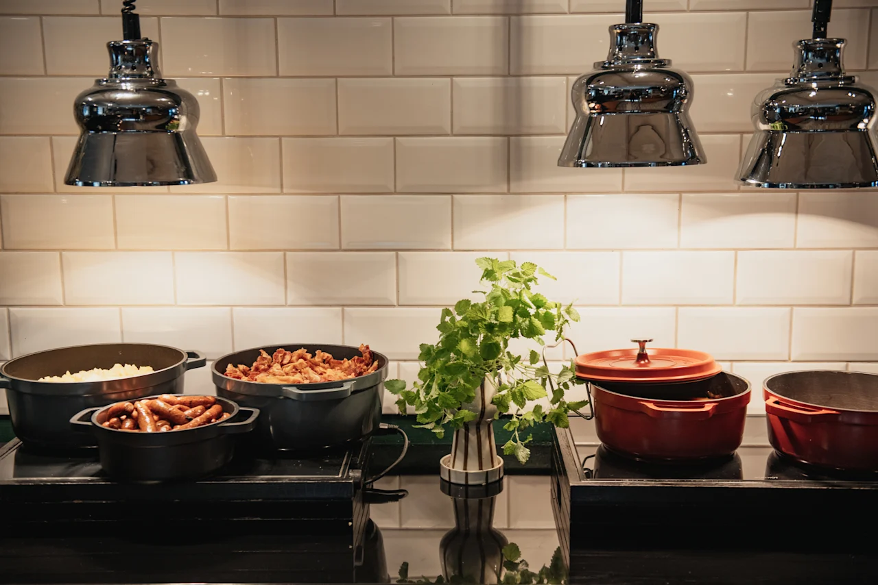 En varm buffé på Home Hotel Grand, Helsingborg, med varma rätter som korv och andra tillagade maträtter, under starka lampor.