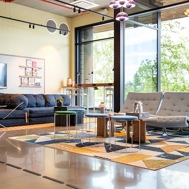 A modern and inviting lounge area with comfortable seating, a large TV, and big windows overlooking lush greenery.