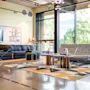 A modern and inviting lounge area with comfortable seating, a large TV, and big windows overlooking lush greenery.