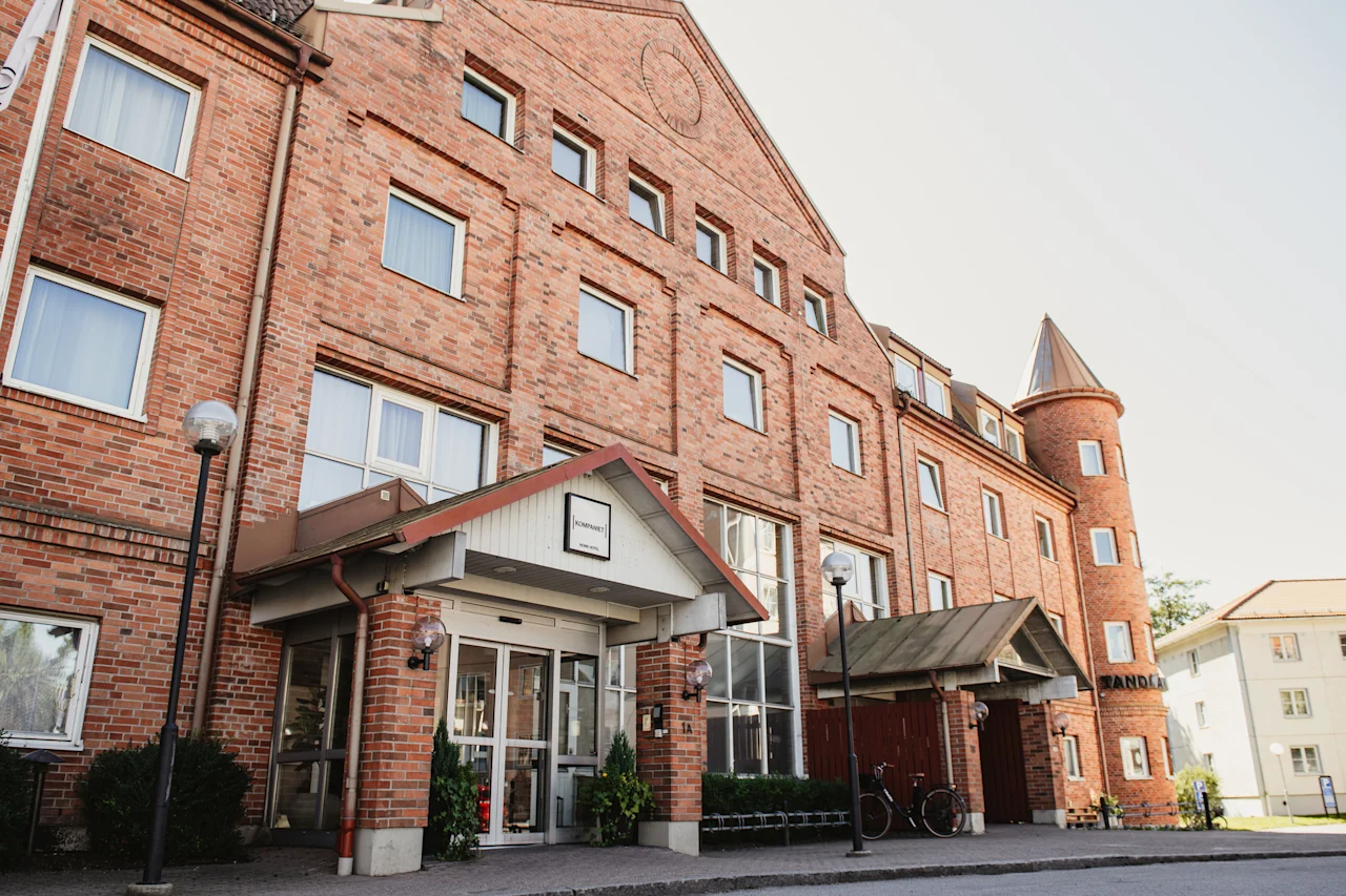En charmig tegelbyggnad med en framträdande entré märkt Kompanihuset och ett runt torn, vilket antyder ett välkomnande hotell.