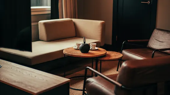 A cozy lounge area with a sofa, two armchairs, and a coffee table with a teapot and cups, suggesting a relaxing break.