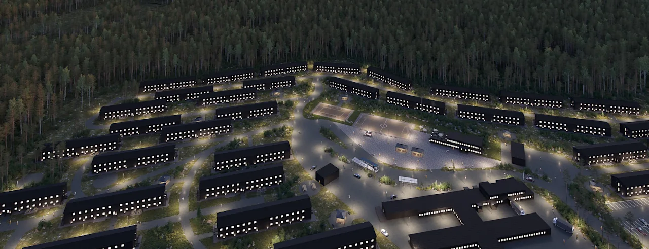 An aerial view of a modern building complex at night, with many illuminated windows, surrounded by a dense forest.