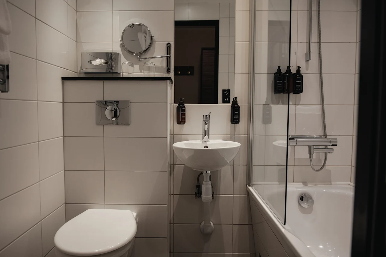 A well-appointed bathroom featuring a toilet, sink with mirror, and a shower-bathtub combination. Ready for use.