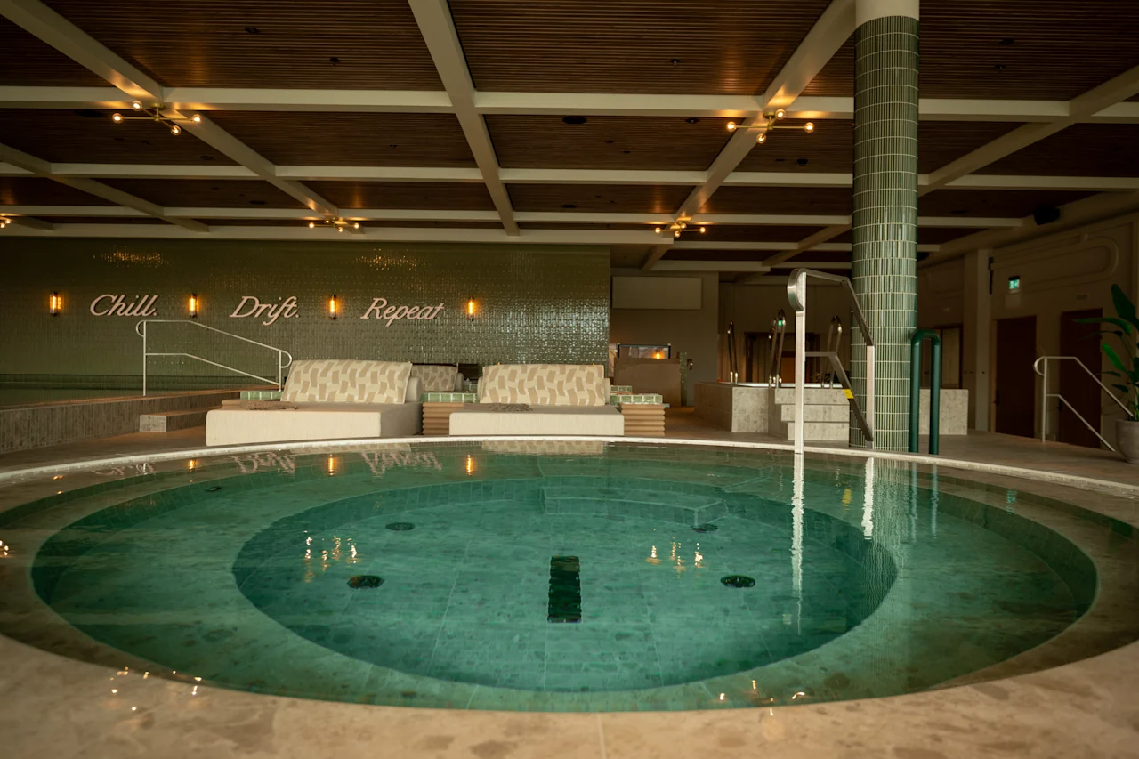 Et rolig syn av The Dock Spa med et stort sirkulært basseng, innbydende salongområder og mottoet 'Chill Drift Repeat'.