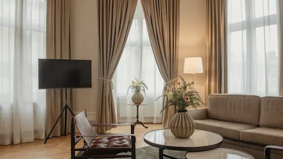 Home Hotel Baltzar - Junior Suite. A welcoming living space featuring a comfortable sofa, television, and sunlit windows.