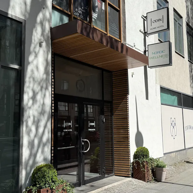 Building entrance with glass doors and a wooden canopy. Signs for HOME HOTEL and WELLNESS are visible, plus a STAR BOWLI graphic.