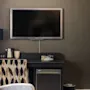 En bekväm hotellrumsinredning med en väggmonterad TV, en förfriskningsstation och en mysig sittplats.