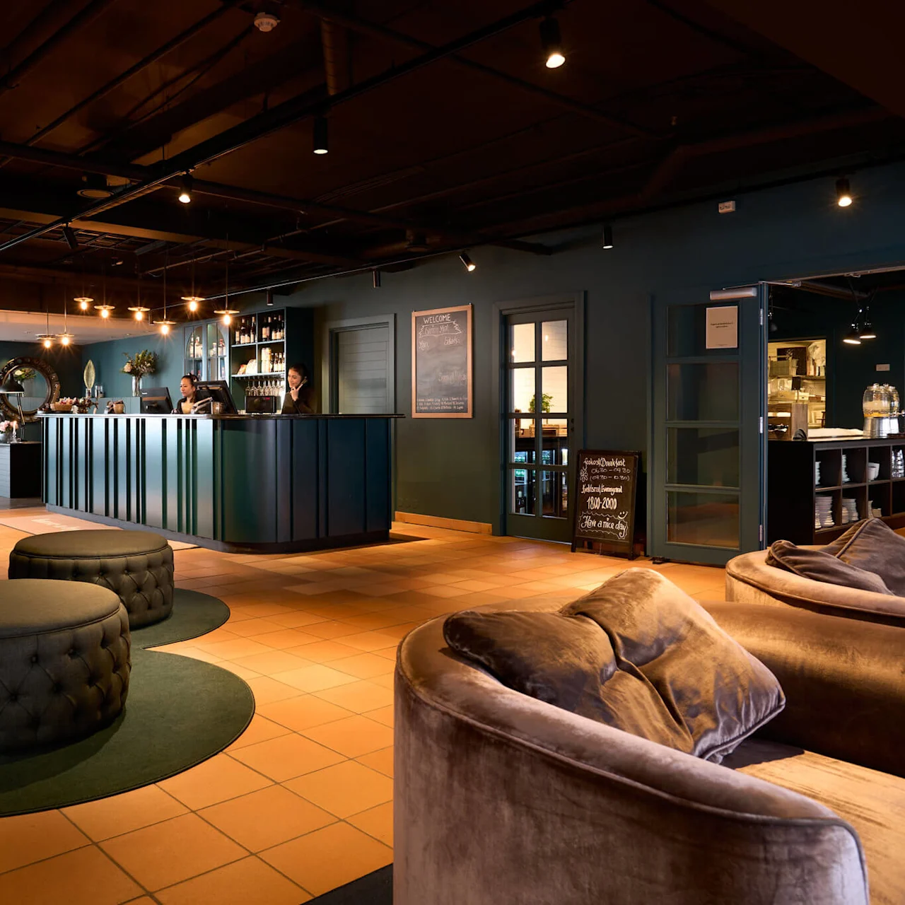 Et hotellobby med en receptionsdisk, bløde siddepladser og dæmpet omgivelsesbelysning.