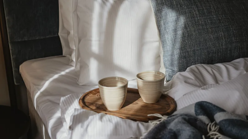 En komfortabel seng med en bakke med to kopper, perfekt til et afslappende øjeblik med en varm drik.