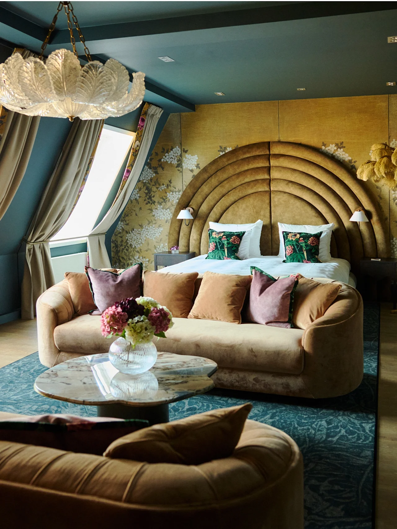 Et luksuriøst hotellrom med en stor seng, en komfortabel sofa og elegant innredning, som skaper en innbydende og overdådig atmosfære.