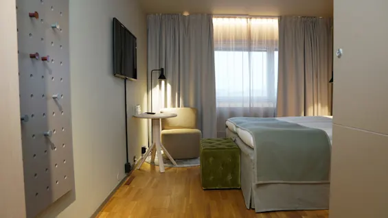 Moderni ja kutsuva hotellihuone, jossa on mukava sänky, pieni oleskelutila ja ikkuna, josta tulee luonnonvaloa.