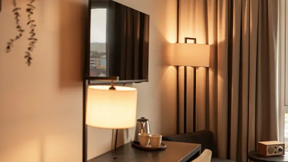 Et hyggeligt hotelværelseshjørne med skrivebord, TV og varm belysning, klar til arbejde eller afslapning.