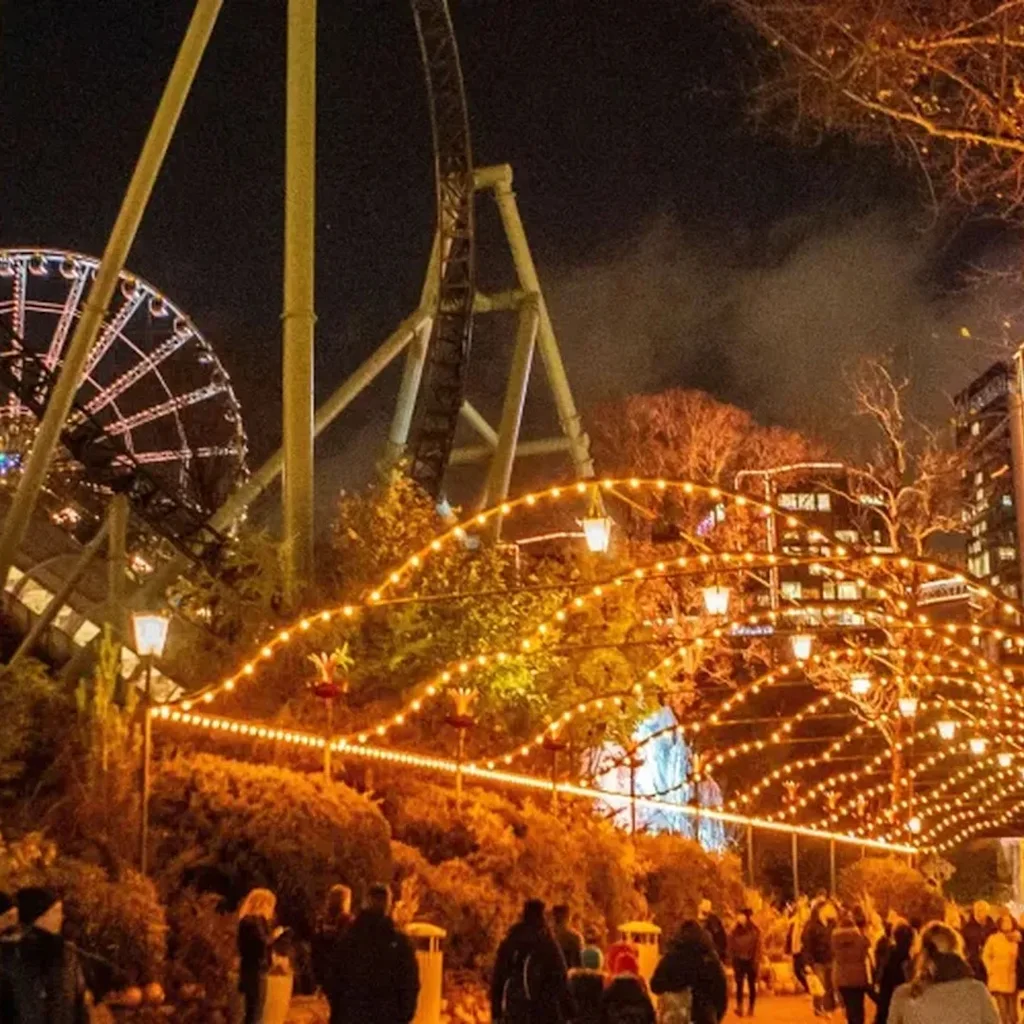 Lisebergs nöjespark i Göteborg på kvällen, med träd som glöder i orange och gyllene ljus under Halloween.