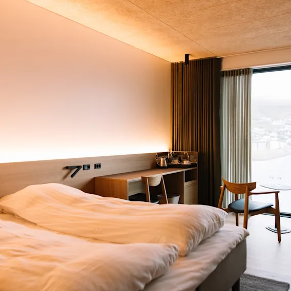 Ett modernt hotellrum med en bekväm säng, ett skrivbord och ett stort fönster med naturskön utsikt.