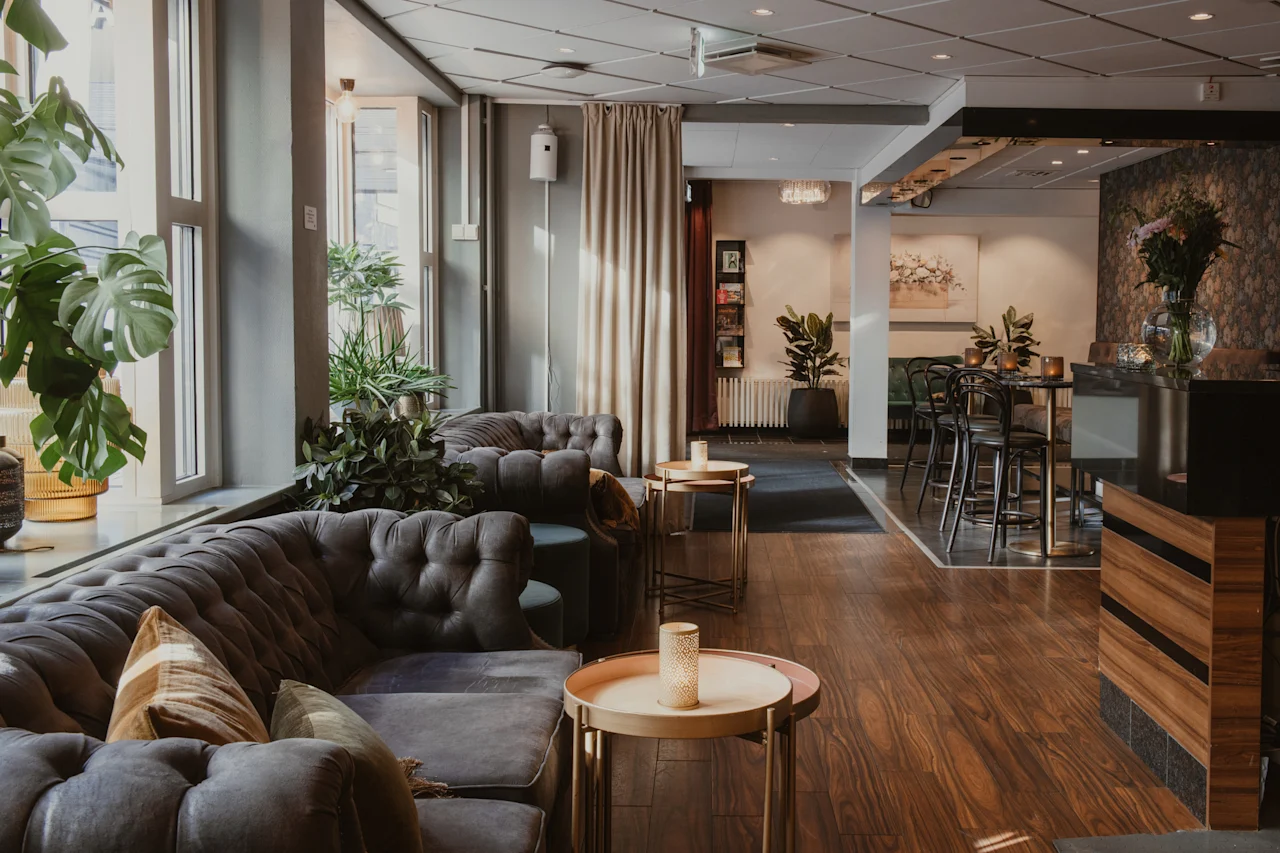 Tyylikäs hotelliaula, jossa on mukavat istuimet, rehevää kasvillisuutta ja tyylikäs baari, luoden kutsuvan tunnelman.