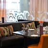 Et koselig restaurantområde med dekkede bord, komfortable båsseter og oransje detaljer.