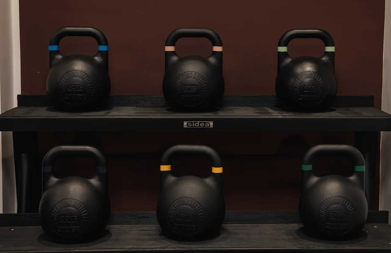 Ett ställ som visar flera kettlebells med färgade handtag, redo för ett träningspass.
