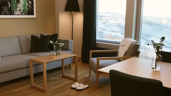Et indbydende værelse med sofa, spisebord og en smuk vinduesudsigt over et sneklædt landskab, perfekt til afslapning.