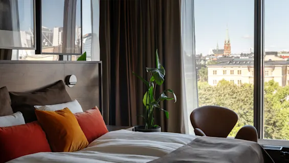 Clarion Hotel Sign - Stratum Suite. A cozy hotel room with a large window offering a city view and a comfortable bed.