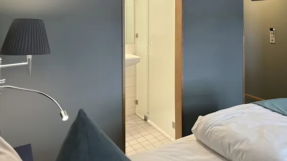 Viihtyisä hotellihuone, jossa sänky ja näkymä moderniin kylpyhuoneeseen.