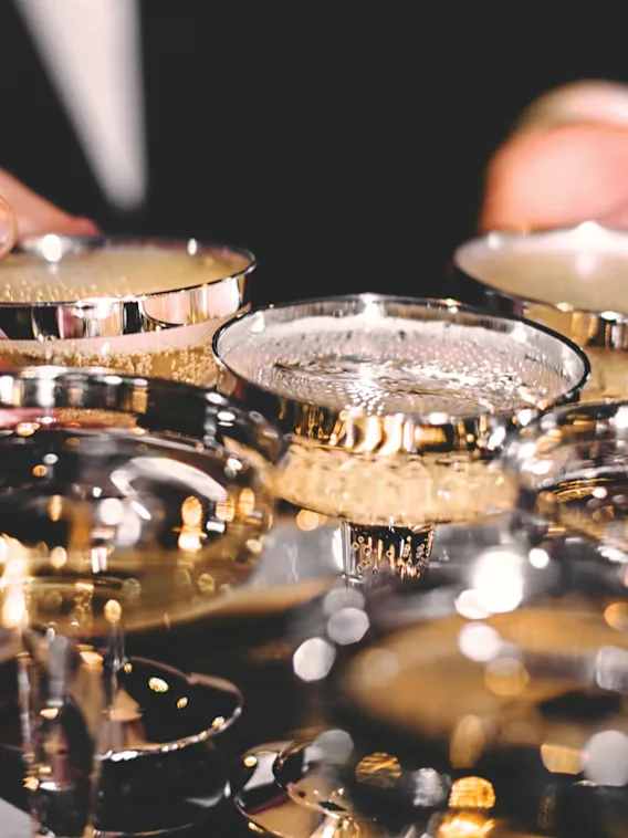 Hands arranging sparkling drinks in elegant glasses on a tray, ready for a celebration.