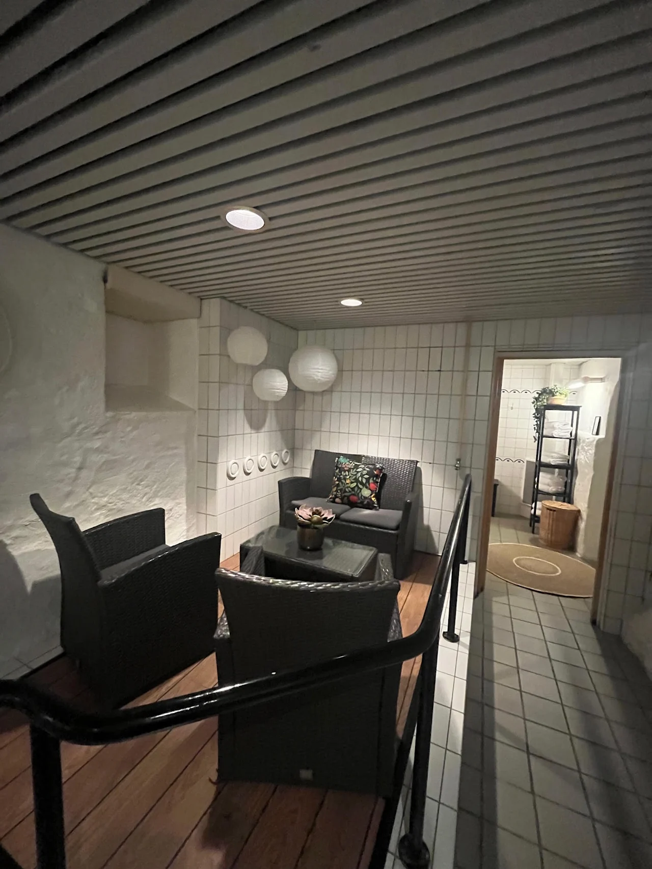 En rolig velværelounge på Home Hotel Bilan med komfortable kurvmøbler, hvite flislagte vegger og myk stemningsbelysning.