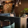 Et varmt og indbydende loungeområde med komfortable siddepladser, blød belysning og dekorative planter, der skaber en hyggelig atmosfære.