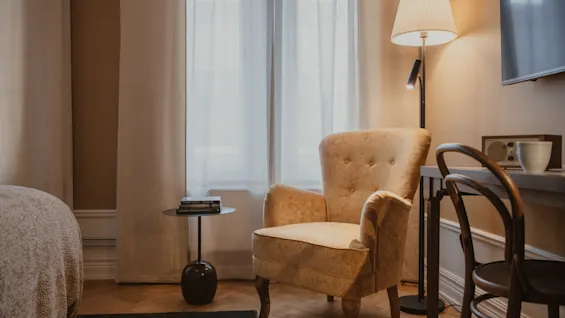 Home Hotel Baltzar - Standard Twin. An inviting hotel room featuring a comfortable armchair, reading lamp, and a desk area.