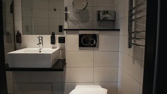 Valoisa ja siisti kylpyhuone, jossa on moderni pesuallas, wc ja seinälle asennettu peili, käyttövalmiina.