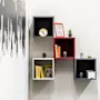 Wall-mounted cube shelves display books, small plants, a clock, and a framed picture. A black-and-white mural of silhouettes decorates the adjacent wall.