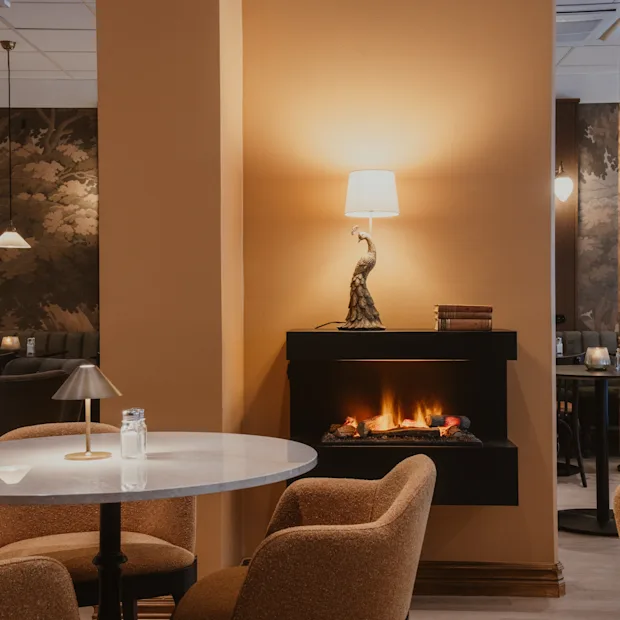 Cozy lounge area at Home Hotel Baltzar with a warm fireplace, comfortable seating, and elegant decor.