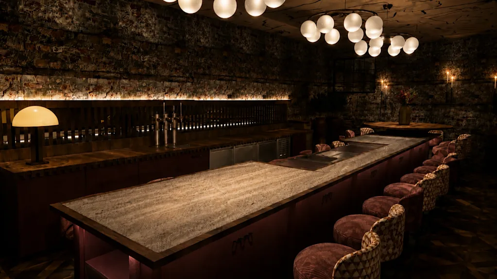 En dunkelt upplyst bar med en lång disk, barstolar och sfäriska taklampor, vilket skapar en mysig och inbjudande atmosfär.