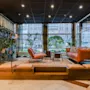 A modern and cozy hotel lobby lounge with leather seating, green plants, and large windows.