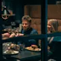 Ryhmä ihmisiä nostaa laseja, hymyillen, istuen kodikkaassa ravintolakojussa lautasilla ruokaa, kuten hampurilaisia, ranskalaisia ja juomia pöydällä.