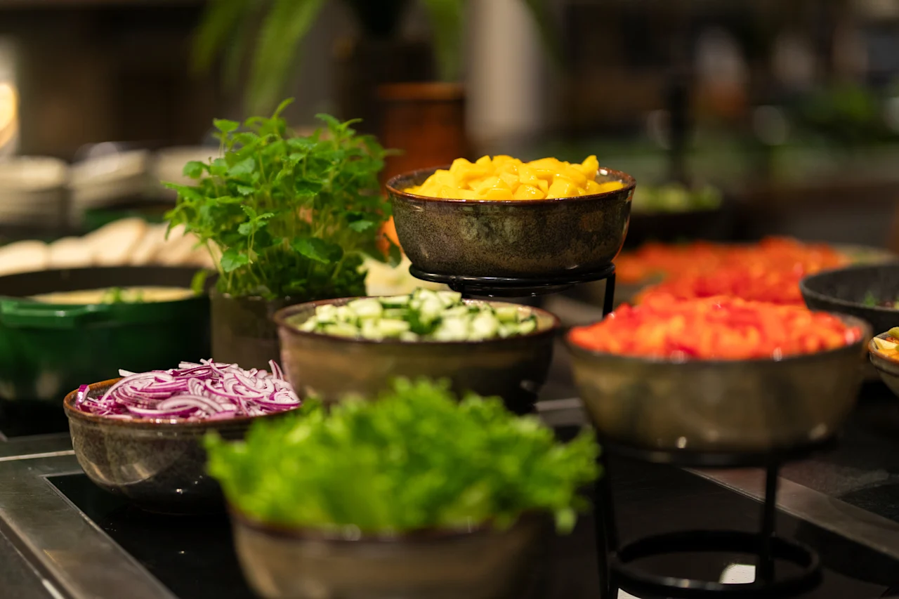 A vibrant buffet at Home Hotel Grand Bodø featuring bowls of fresh chopped vegetables, fruits, and leafy greens, ready for guests to enjoy.