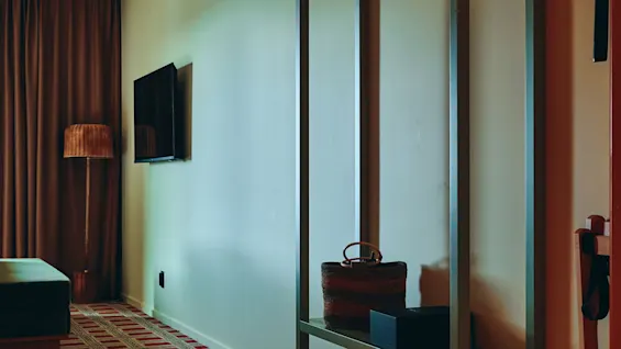 Et koselig rom med mønstret teppe, TV og klesstativ, klart for en gjests opphold.