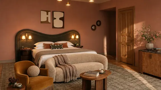 Ett stilfullt hotellrum med en stor säng, soffa och varm belysning. Våra rum tar fortfarande form visualiseringar, inte fotografier.