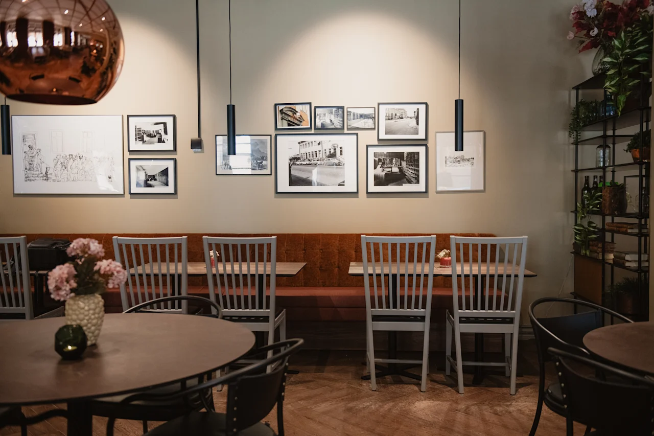 En varm og innbydende restaurant eller kafé med komfortable sitteplasser, dekorert med innrammede kunstverk og planter, klar for gjester.