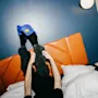 Henkilö rentoutumassa hotellisängyssä jalat ilmassa värikkäät tohvelit jalassaan.