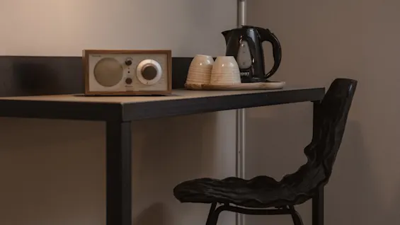 Viihtyisä työpöytäalue, jossa on lämmin lamppu, vintage-radio, vedenkeitin kuppeineen ja ainutlaatuinen musta tuoli, täydellinen rentouttavaan oleskeluun.