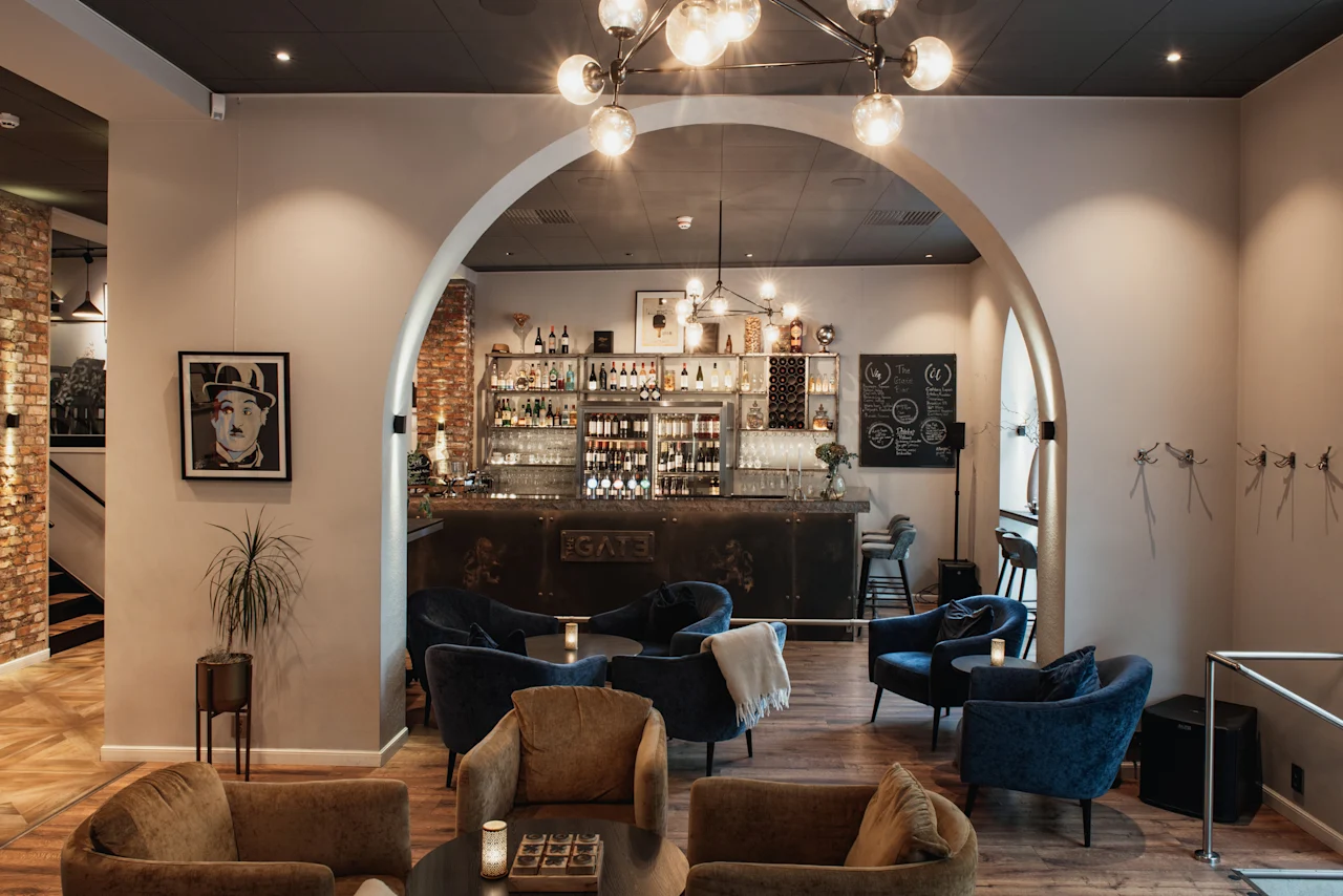 En stilfuld hotellounge på Home Hotel Norre Park med komfortable siddepladser og en velassorteret bar, der inviterer gæster til at slappe af.