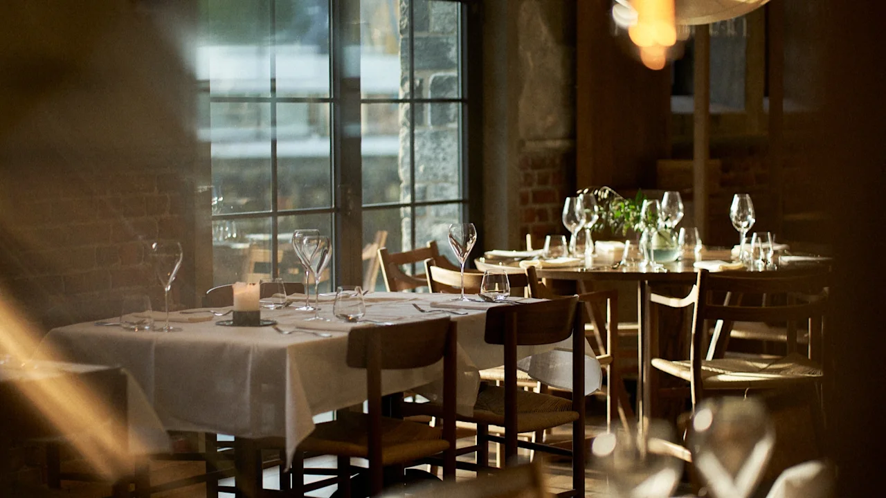 Et varmt og indbydende spiseområde på Sjøbua ved Hotel Brosundet i Ålesund, med dækkede borde og blød belysning.