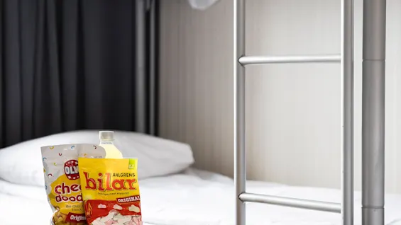 Et koselig rom med køyeseng og snacks på et bord, som gir en avslappet atmosfære. Scenen antyder et behagelig sted for å slappe av eller nyte snacks.