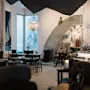 Moderne caféinteriør med eklektisk dekoration og en lysarmatur, store vinduer viser en snedækket skov. Vægtekst: "35 000 tonnes of snow and ice, 600 tons of pure work...ICEHOTEL built in 1989."