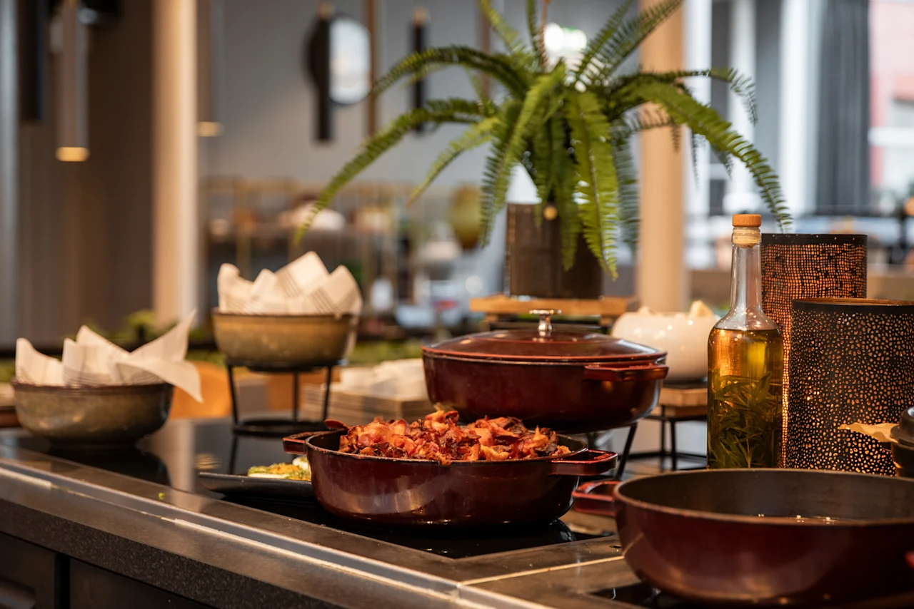 A beautifully arranged warm buffet featuring savory dishes and fresh oil, inviting guests at Home Hotel Grand Bodø.