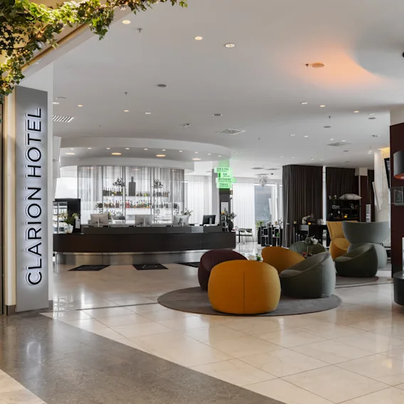 En ljus och modern hotellobby med bekväma sittplatser, en bar och dekorativ belysning, vilket skapar en inbjudande atmosfär.